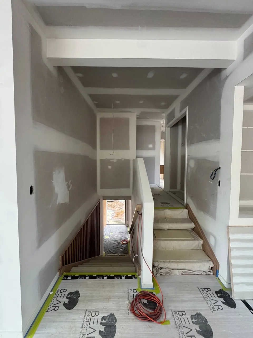 Interior mid-build, floors protected with plastic sheeting before painting