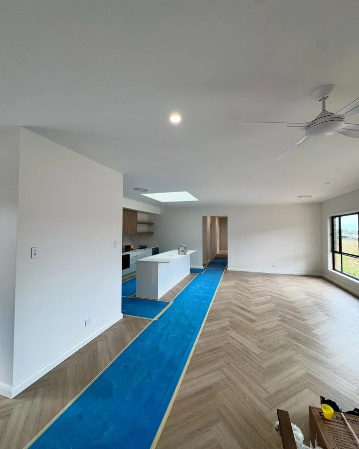 Finished open-plan living space with herringbone floor and white walls